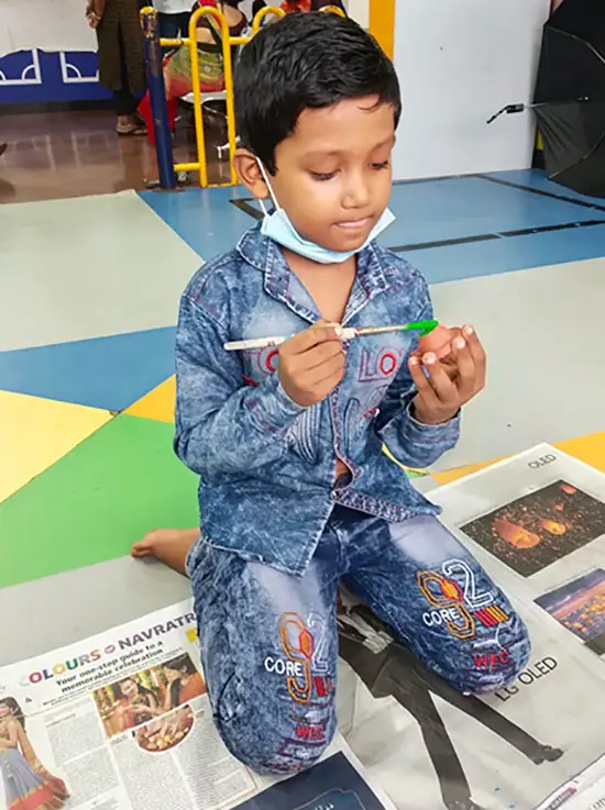 Kid painting a Diya at TMC, Mumbai