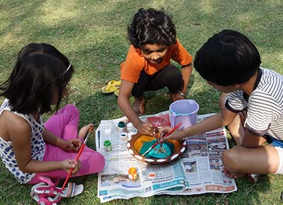 Children paint earthen pots on Holi festival